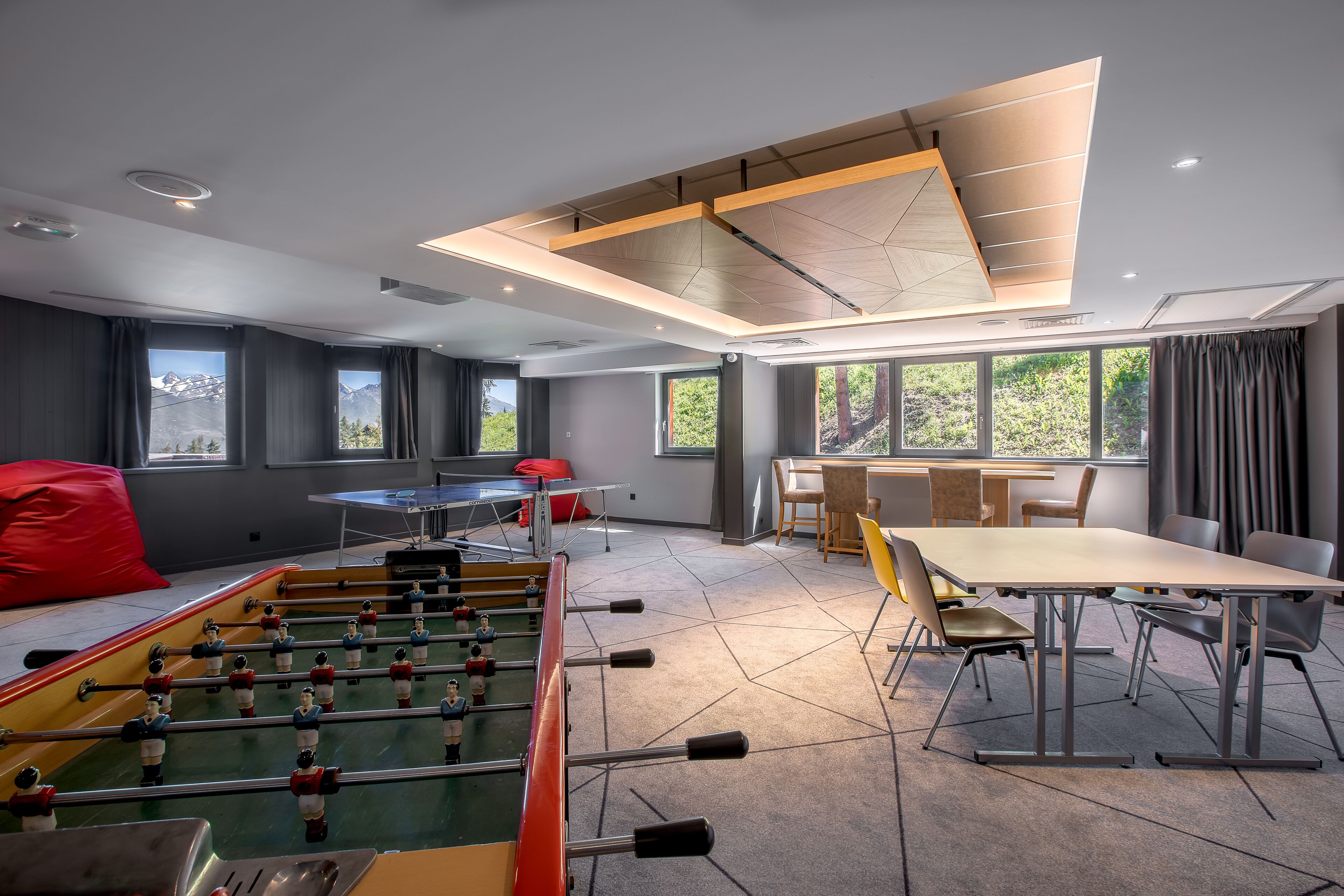 Ein modernes Zimmer mit Tischfußball, Pongtisch und Essbereich mit Stühlen und Tisch.
