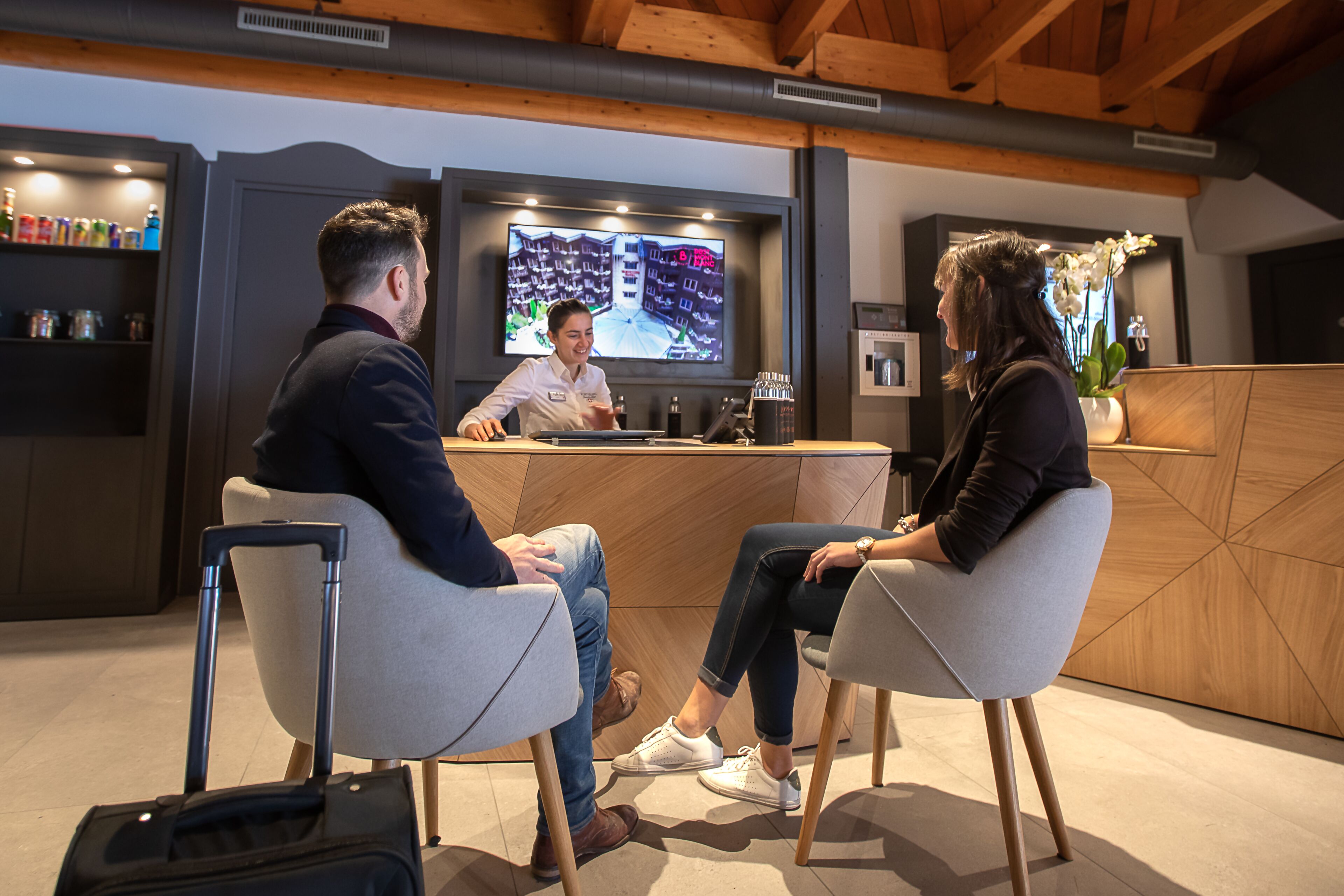 A reception area with a reception desk, a television screen, and a plant.