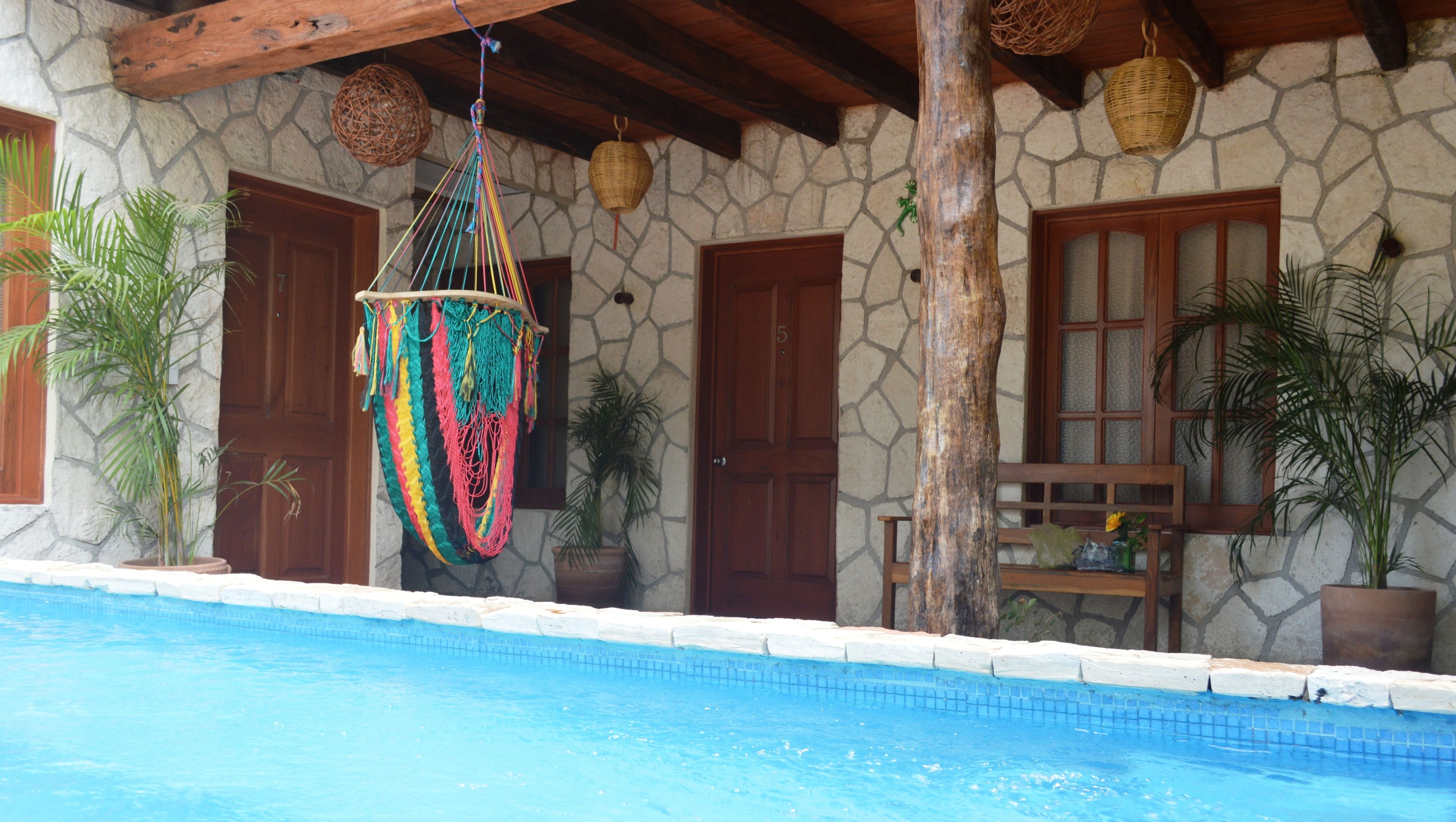 Un edificio de piedra con piscina, puertas de madera y decoraciones colgantes.