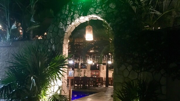 Un área de restaurante al aire libre con arcos de piedra, mesas y sillas.