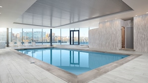 Una piscina interior moderna con vistas a la ciudad, amplias ventanas y un diseño contemporáneo.