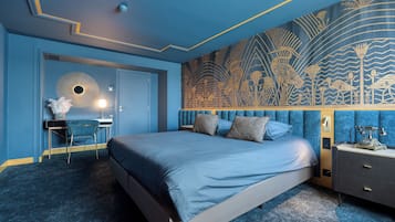 A bedroom with a bed, a desk, and a nightstand.