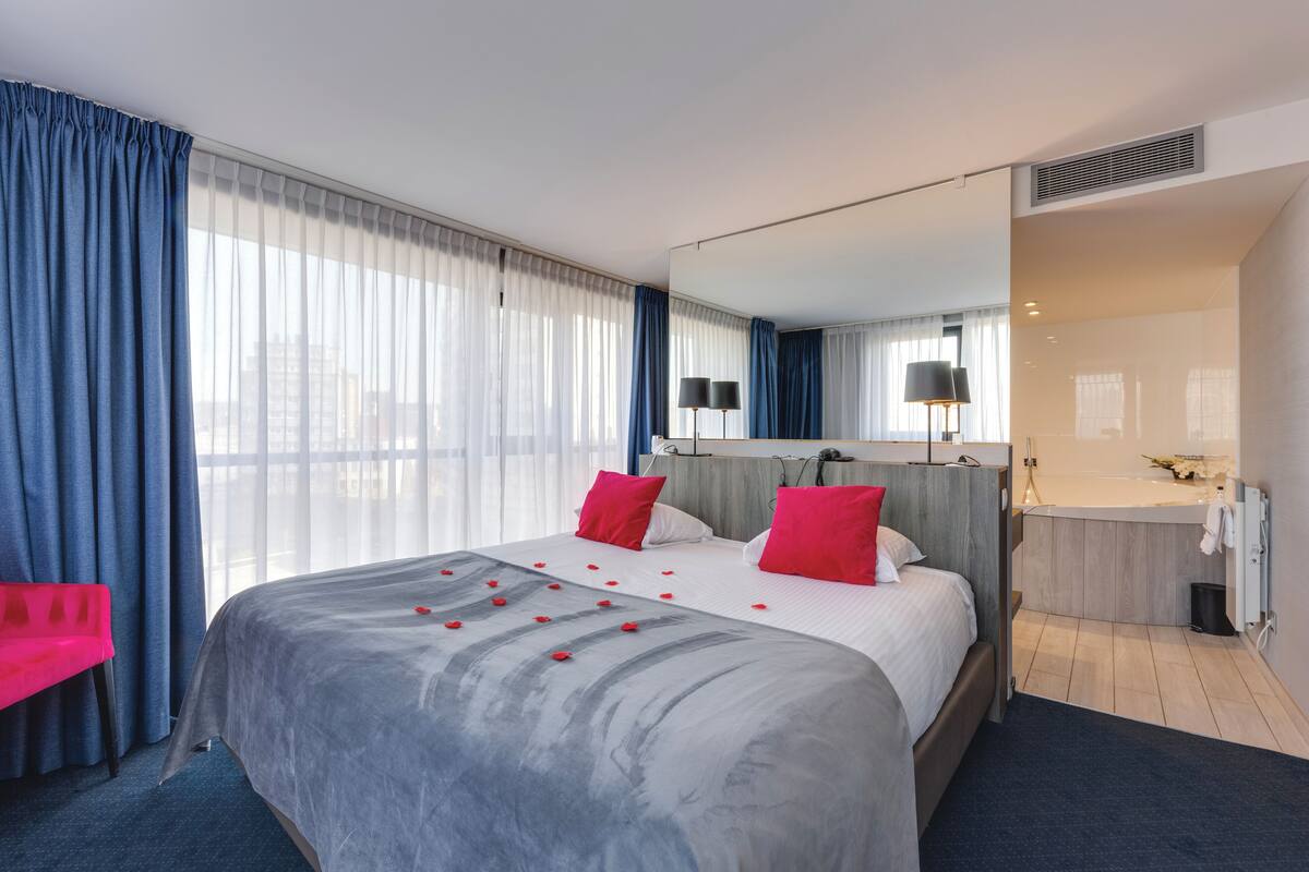Une chambre d’hôtel moderne dotée d’un grand lit, d’une salle de bain et offrant une vue sur la ville.