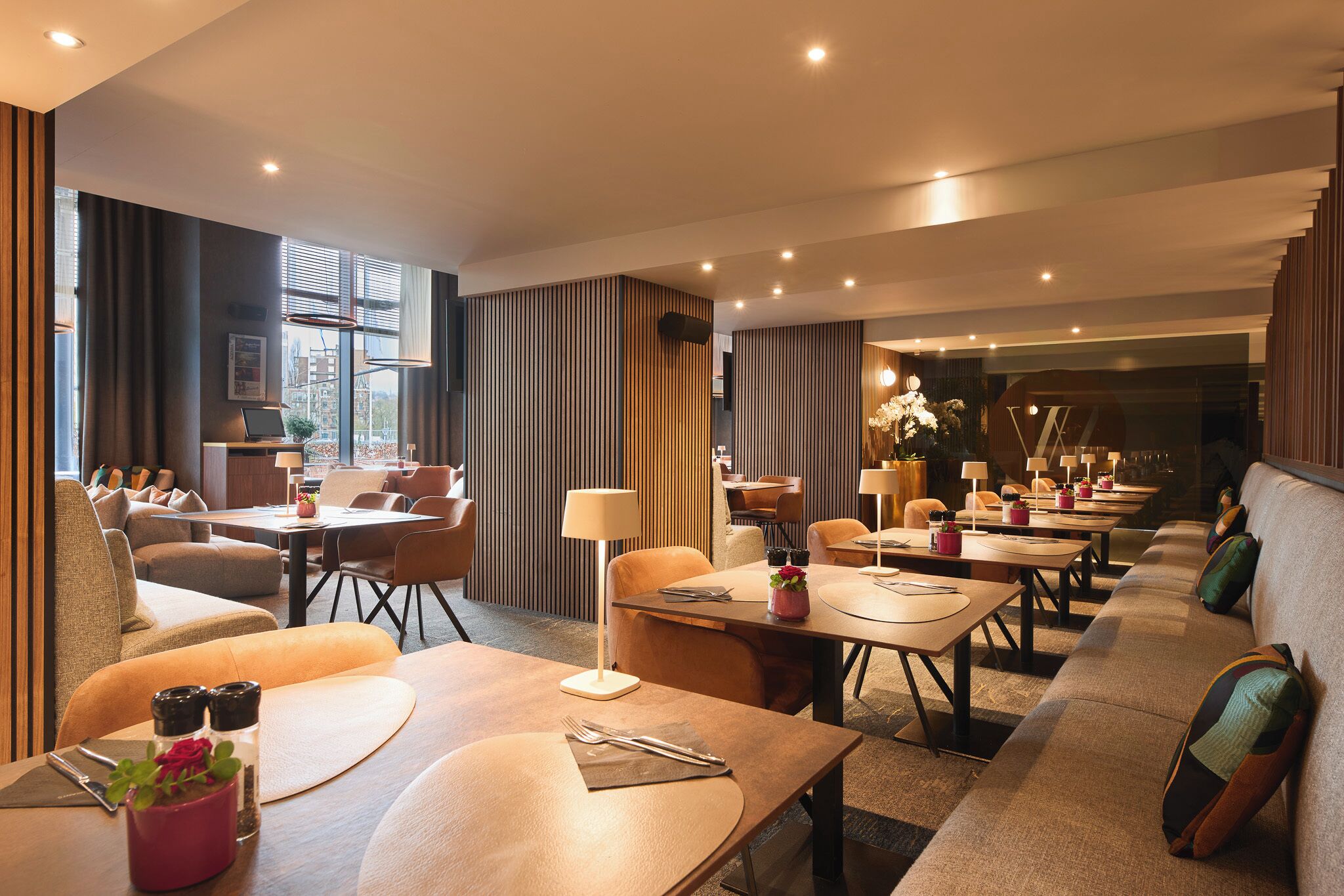 A modern hotel dining area with multiple tables, chairs, and a sofa.