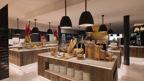 Una cocina moderna con encimeras de madera, lámparas colgantes negras y una isla central con pan y pasteles.