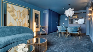 Una sala de estar moderna con un sofá azul, una mesa de centro y una zona de comedor con sillas.