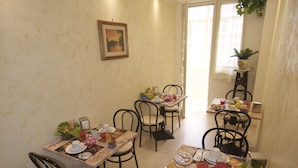 Un comedor con una mesa dispuesta para cuatro personas, sillas, un cuadro en la pared y un letrero que indica una zona de café.