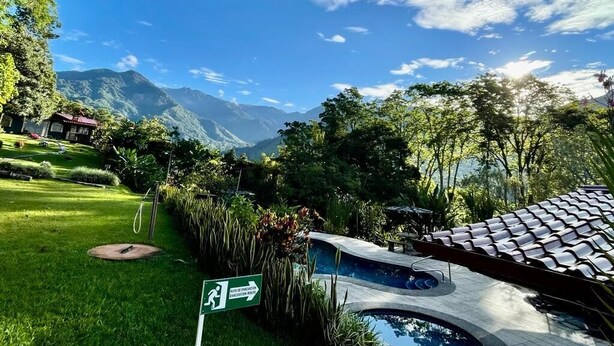Uma área de piscina com vista desobstruída para montanhas ao fundo, cercada por vegetação exuberante e céu limpo.