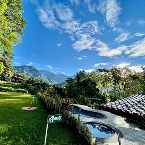 A pool area with a clear view of mountains in the background, surrounded by lush greenery and a clear sky. - Hotel de Montaña El Pelicano (Rivas)