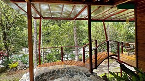 Um espaço ao ar livre coberto com lareira de pedra, vigas de madeira e telhado de metal.