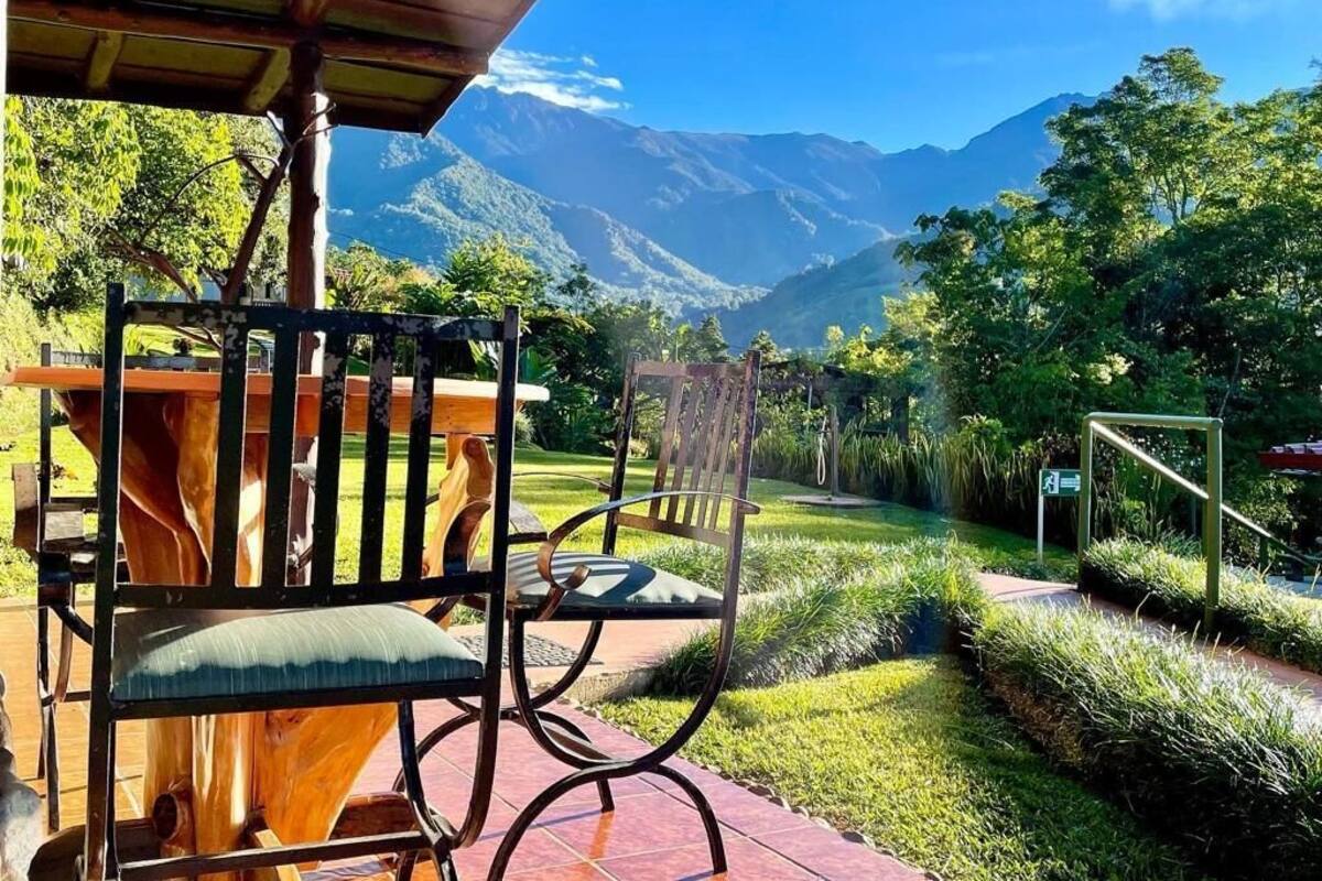 Un conjunto de banco y silla de madera en un jardín con vista a la montaña.