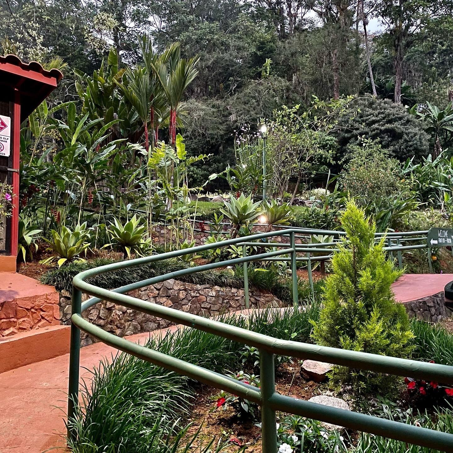A garden with a metal railing, various plants, and a sign that reads "WELCOME".