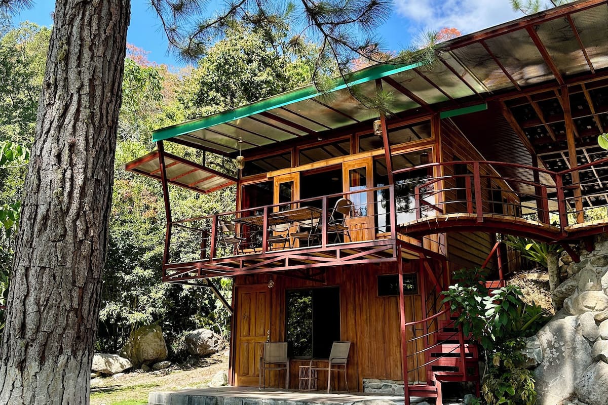 Una cabaña rústica con fachada de madera, un balcón con asientos y una base de piedra.
