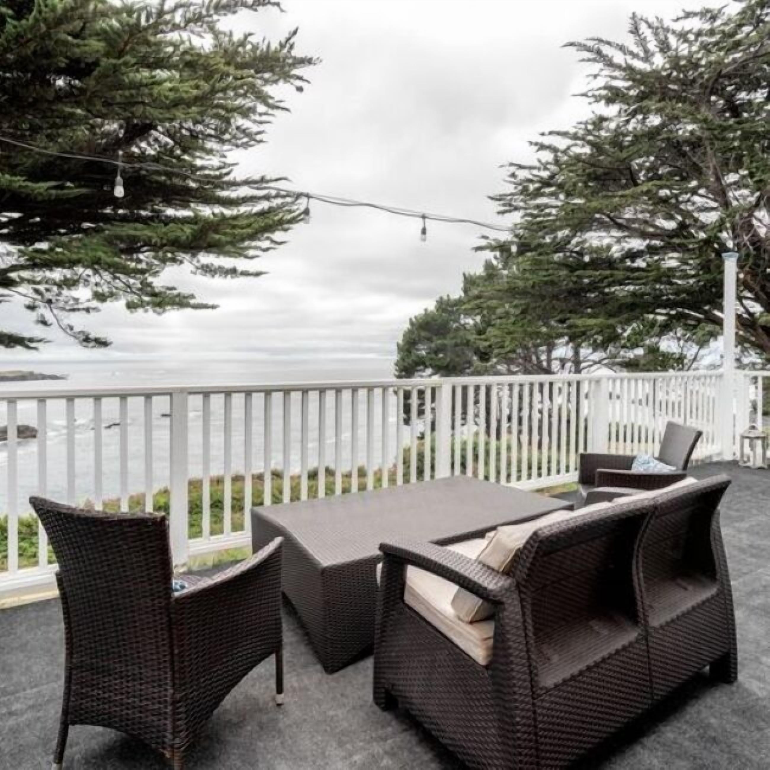 An outdoor seating area with wicker furniture and a view of the ocean.