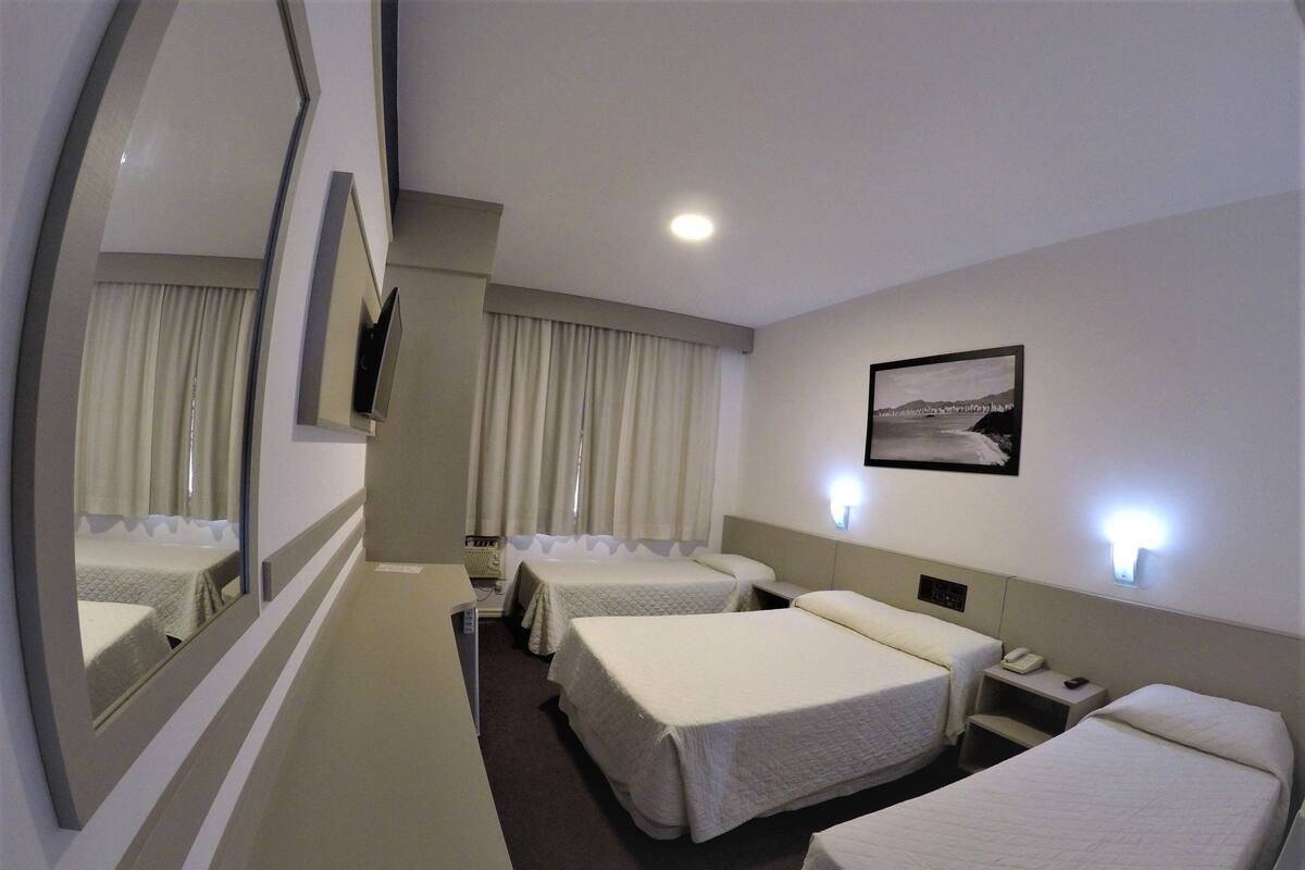 Ein Hotelzimmer mit zwei Betten, einem großen Spiegel, einem Nachttisch mit Telefon und einer Wandlampe.