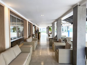 A covered outdoor seating area with wicker furniture and a view of the street. - Hotel Gracher Praia (Balneário Camboriú)