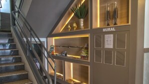 A staircase with a handrail leading to a reception area with a counter and a display of items. - Hotel Gracher Praia (Balneário Camboriú)