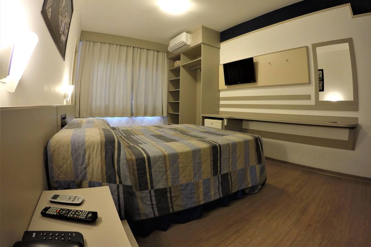 Ein Hotelzimmer mit Bett, Schreibtisch, Fernseher und Kleiderschrank.