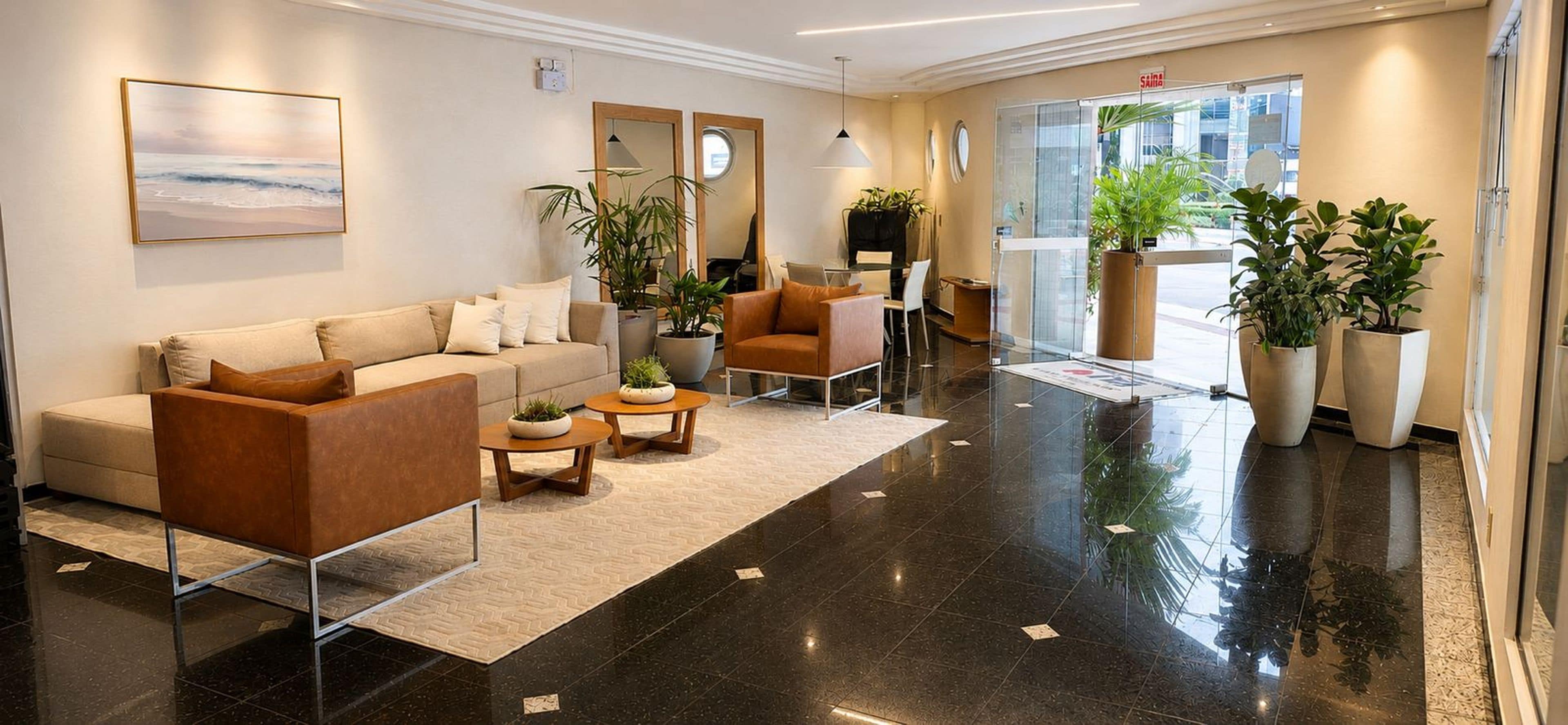 A hotel lobby with a sofa, armchairs, a coffee table, and potted plants.