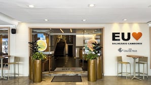 The entrance to a hotel with a glass door, a reception desk, and a sign indicating the hotel name.
