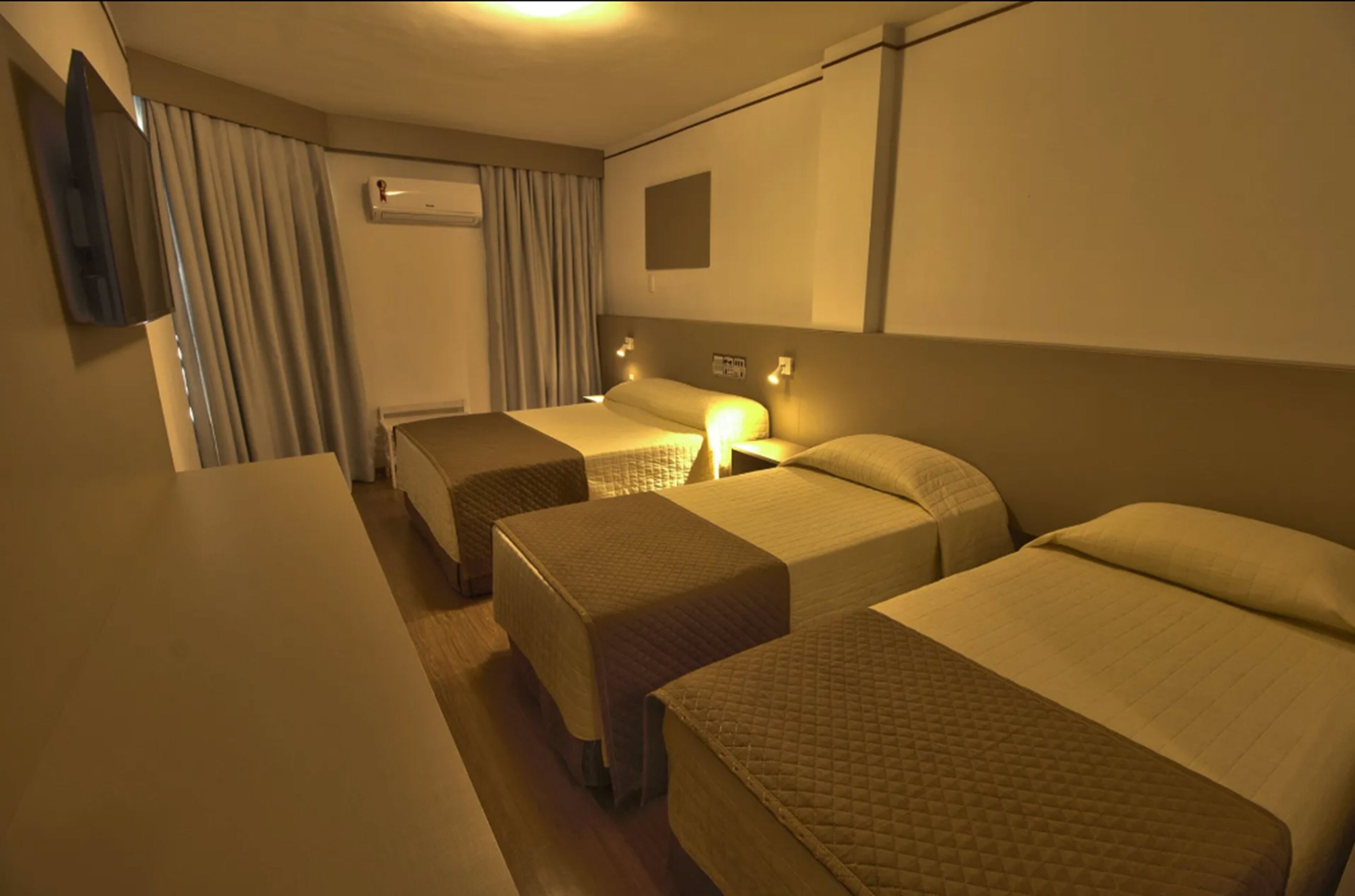 A hotel room with two beds, a flat-screen TV mounted on the wall, and a bedside table.
