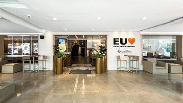 Un hall d’hôtel comprenant un comptoir d’accueil, un espace salon et un escalier menant à l’étage supérieur.