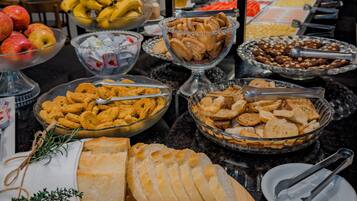 Een buffet met diverse gerechten, waaronder brood, gebak en fruit.