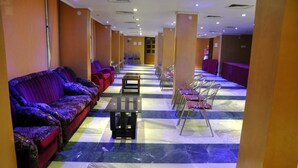 A hotel lobby with a checkered floor, purple sofas, and metal chairs. - Hotel Raj Palace (Barasat)