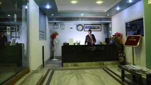 A reception desk with a sign, a clock, and a framed picture on the wall. - Hotel Raj Palace (Barasat)