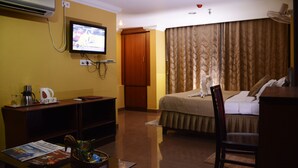A hotel room with a bed, a desk with a computer, a television, and a wardrobe. - Hotel Raj Palace (Barasat)