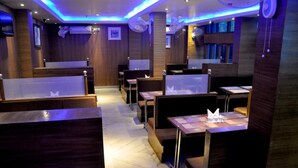 A restaurant with wooden paneling, booths, and tables. - Hotel Raj Palace (Barasat)