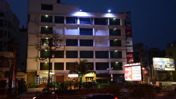 A multi-story hotel with a Coca-Cola sign, a visible restaurant, and a sign for Hotel Raj Palace. - Hotel Raj Palace (Barasat)