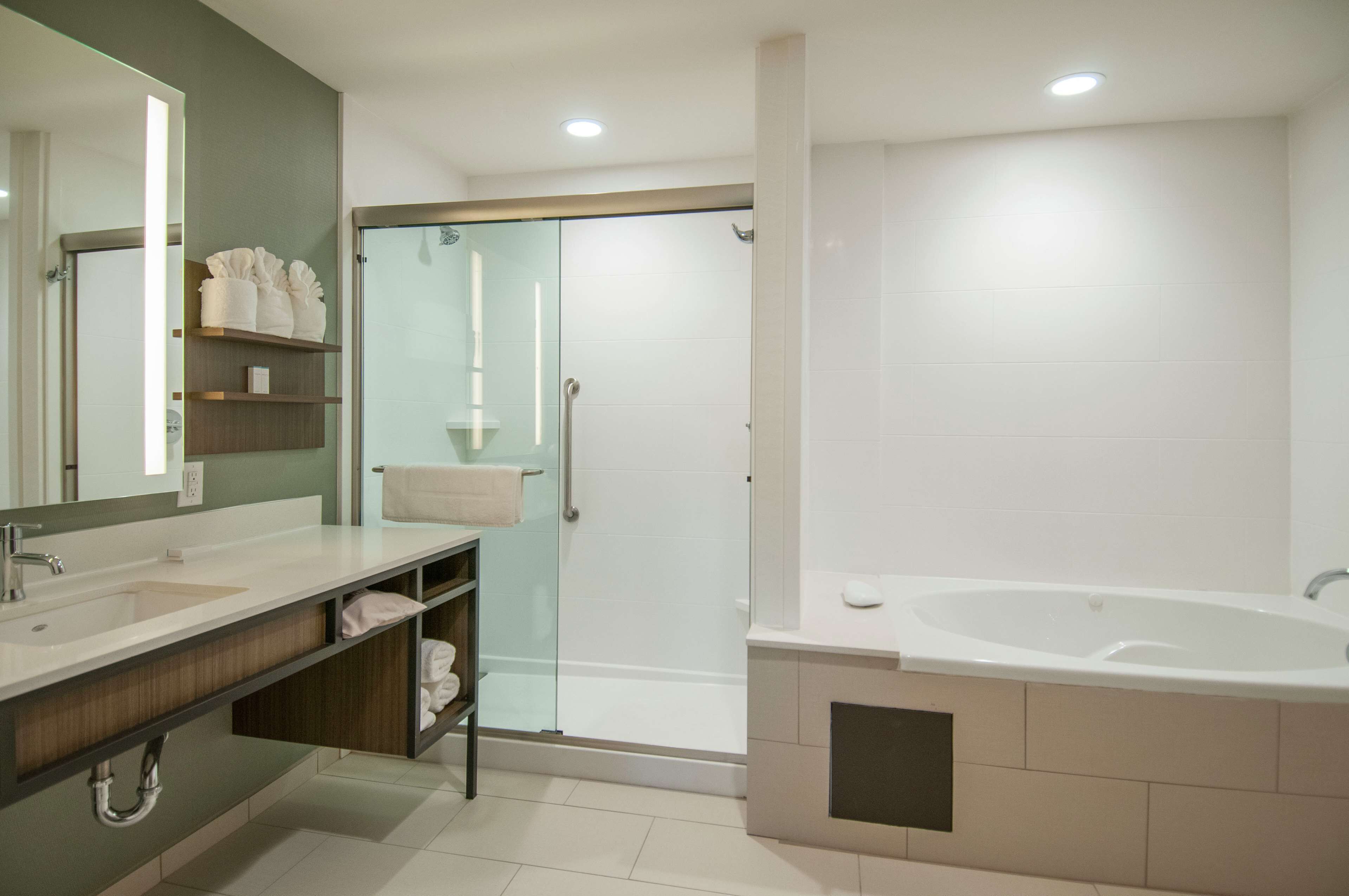 Un baño moderno con un espejo grande, dos lavamanos, una ducha con cerramiento de vidrio y una bañera independiente.