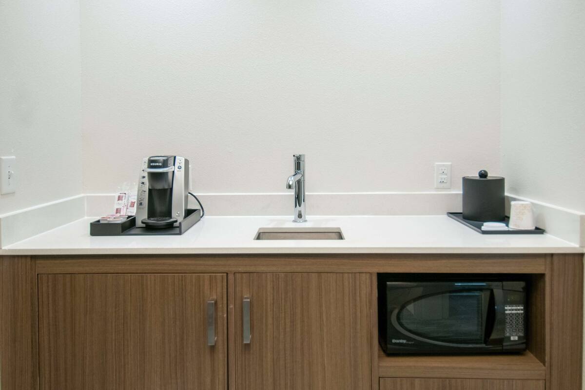 A modern kitchen with a coffee maker, sink, and microwave.
