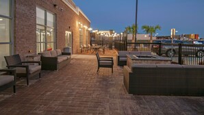 An outdoor patio area with brick flooring, wicker furniture, and string lights.