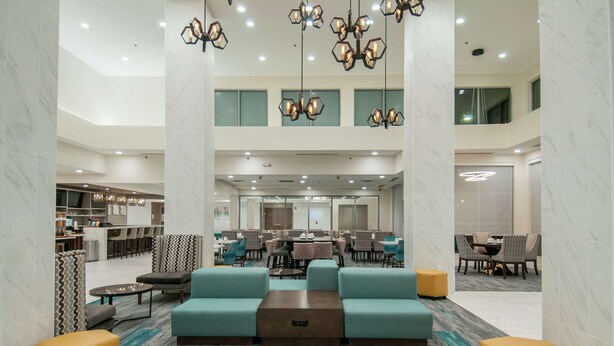 A spacious lobby with seating areas, a central coffee table, and a modern chandelier.