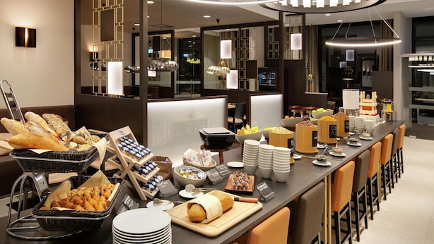 A buffet setup with various food items and a modern interior design. - Hilton Garden Inn Zurich Limmattal (Spreitenbach)