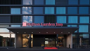The exterior of the Hilton Garden Inn with a red carpet entrance, large windows, and a modern architectural design. - Hilton Garden Inn Zurich Limmattal (Spreitenbach)