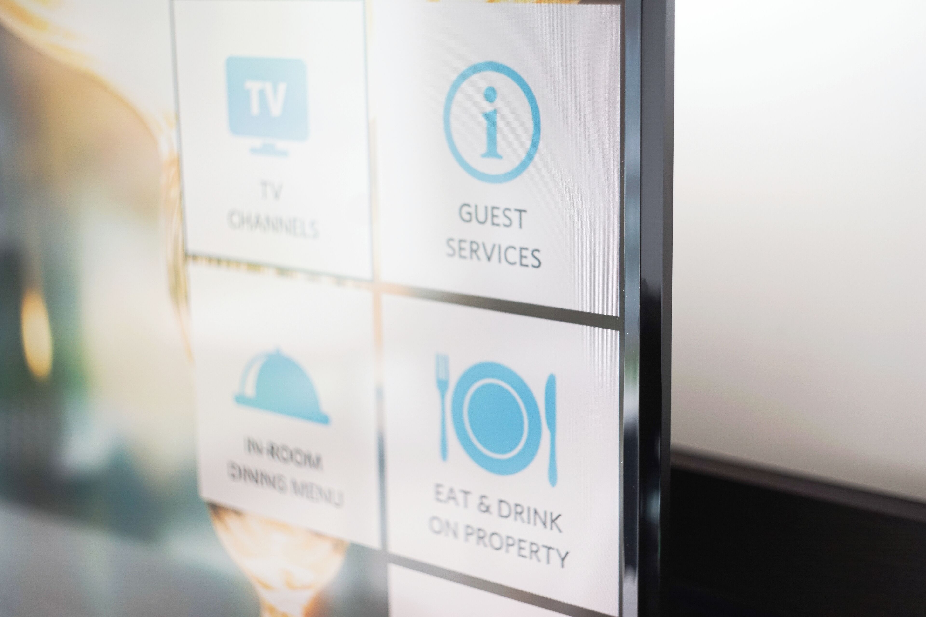 A sign with icons indicating TV channels, guest services, in-room dining menu, and eat & drink on property.