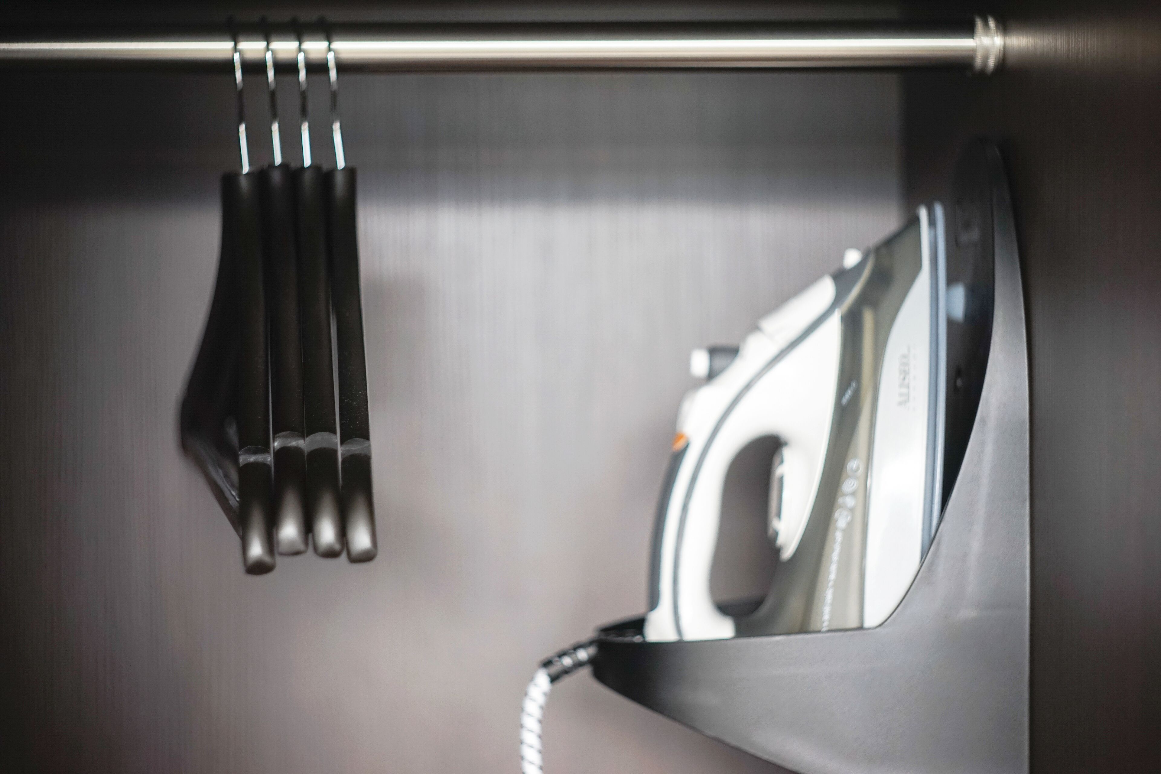 A metallic iron with a cord, mounted on a wall.
