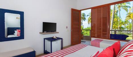 A hotel room with a bed, a television, a small table, and a window with a view of palm trees.