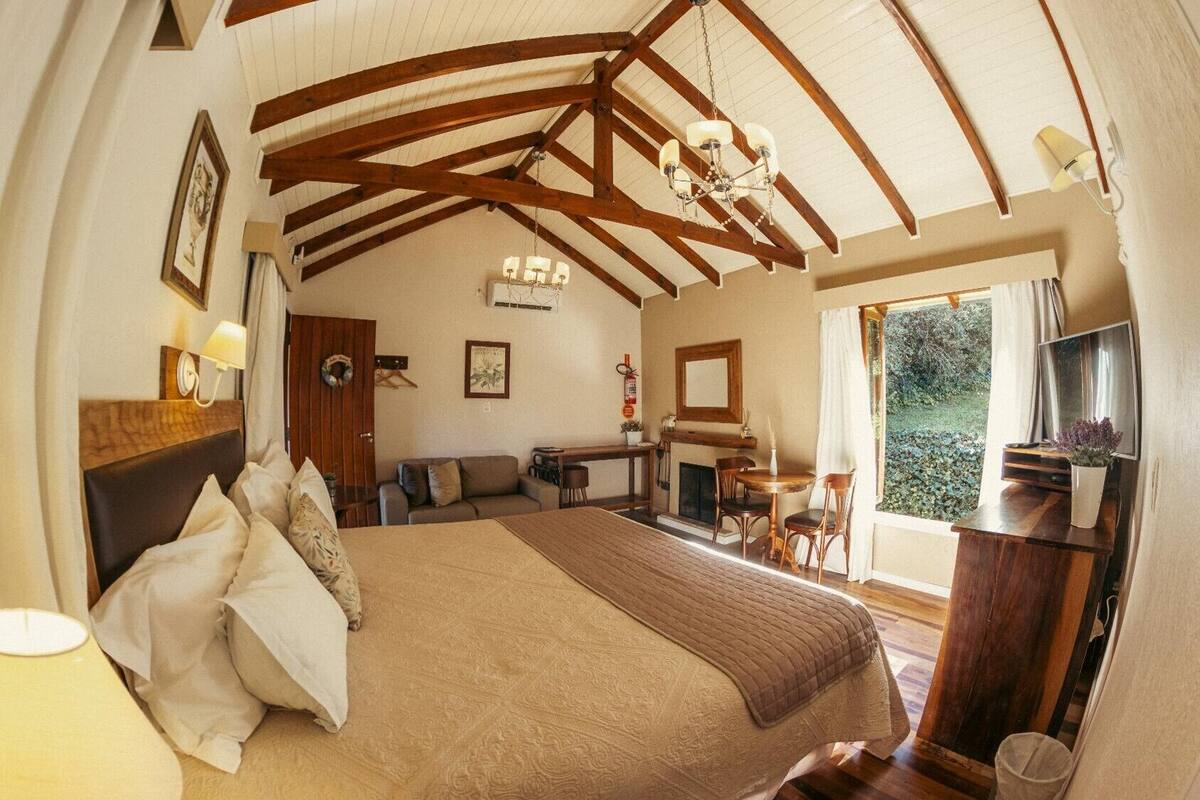 A spacious bedroom with a large bed, a dining area, and a fireplace.