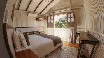 A bedroom with a wooden bed, a nightstand, a desk, and a window with shutters.