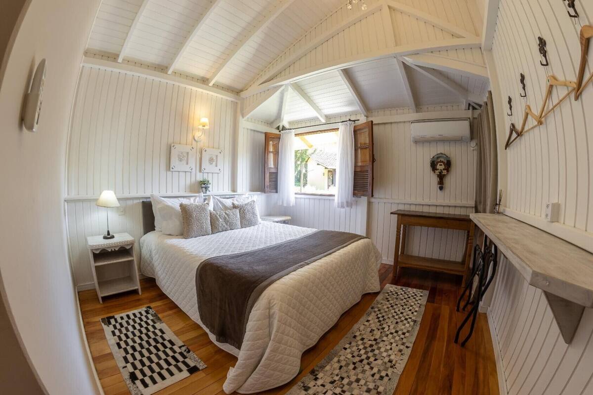 A cozy bedroom with a bed, bedside tables, a lamp, and a window with curtains.