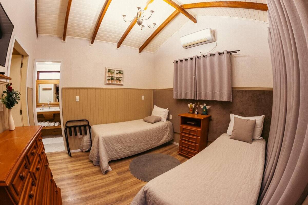 A room with two beds, a wooden dresser, a mirror, and a ceiling fan.