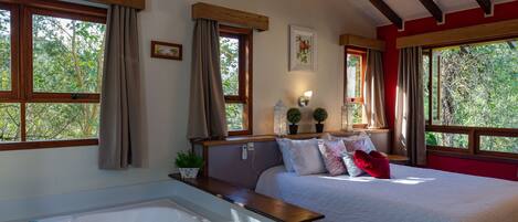 A bedroom with a large bed, a wooden headboard, a bedside table, a nightstand, a lamp, and a window with curtains.