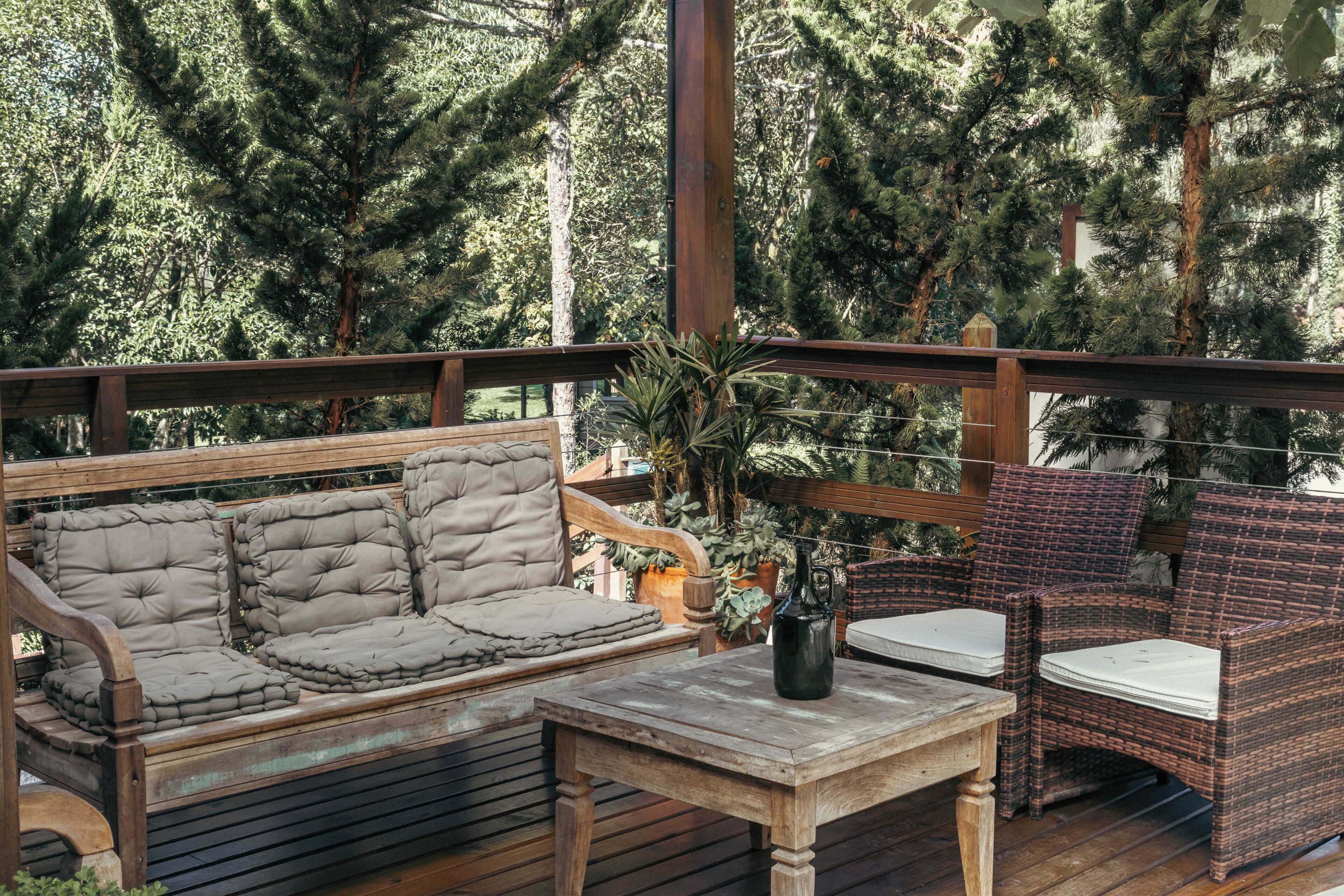 A wooden deck with a sofa and chairs, surrounded by trees.
