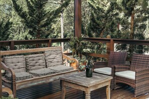 A wooden deck with a sofa and chairs, surrounded by trees. - Serra Bela Eco Pousada (Urubici)