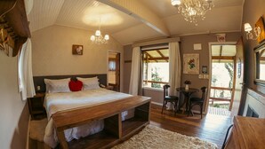 Une chambre à coucher avec un lit en bois, une petite table avec des chaises, un lustre et une vue sur l’extérieur.