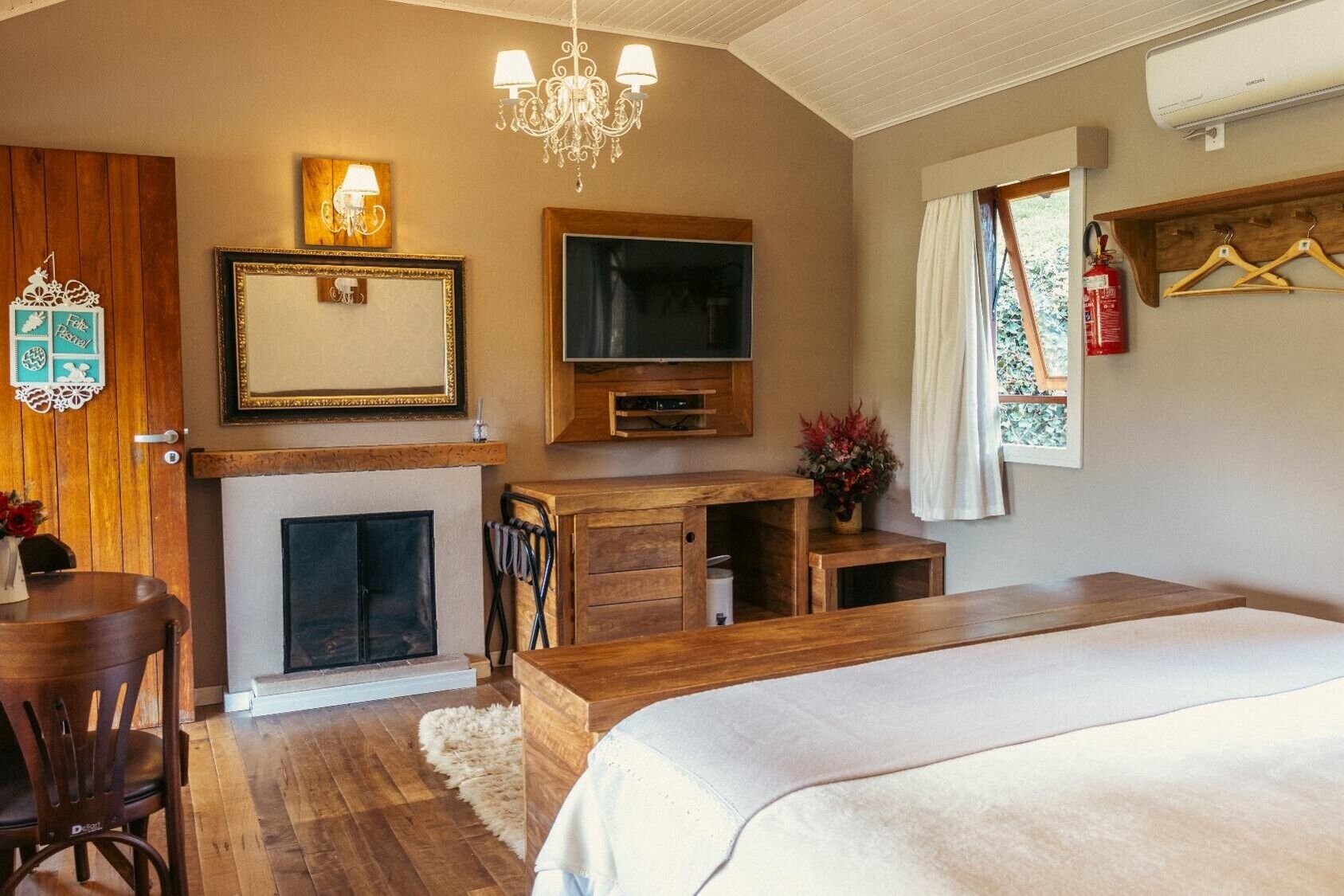 A cozy bedroom with a large bed, a fireplace, a television, and wooden furniture.